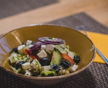 A delicious Greek salad featuring feta cheese, olives, and fresh vegetables in a rustic bowl.