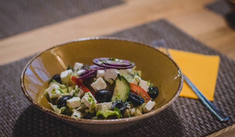 A delicious Greek salad featuring feta cheese, olives, and fresh vegetables in a rustic bowl.