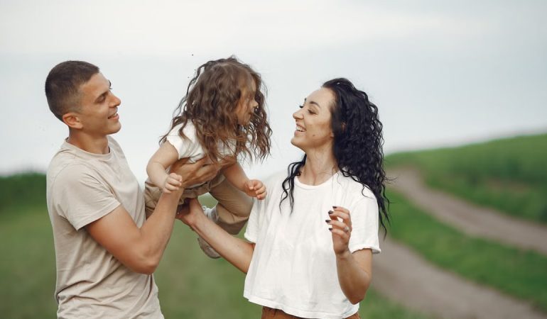 A joyful family moment outdoors with parents playing with their daughter.